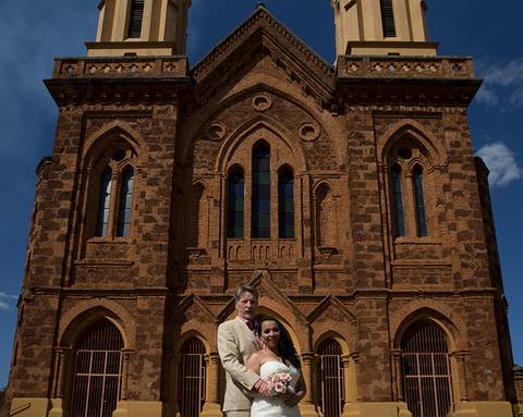 Noivos posam abraçados em frente igreja São Domingos - Uberaba. Ao fundo se vê toda linda construção da igreja'