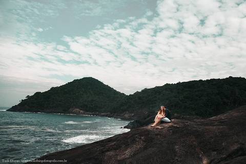 Ensaio dos Noivos em riviera de são lourenço são paulo bertioga ao nascer do sol durante o ensaio pré-wedding na praia no por do sol com pedras montanhas arvores'