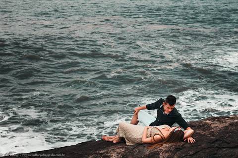 Ensaio dos Noivos em riviera de são lourenço são paulo bertioga ao nascer do sol durante o ensaio pré-wedding na praia no por do sol com pedras montanhas arvores'