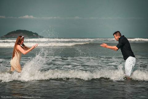 Noivos brincando no mar na Praia em riviera de são lourenço são paulo bertioga ao nascer do sol durante o ensaio pré-wedding na praia no por do sol com pedras montanhas arvores'