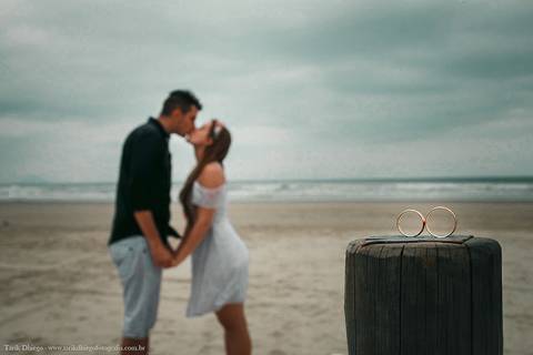 Beijos dos noivos com aliança na Praia em riviera de são lourenço são paulo bertioga ao nascer do sol durante o ensaio pré-wedding na praia no por do sol com pedras montanhas arvores'