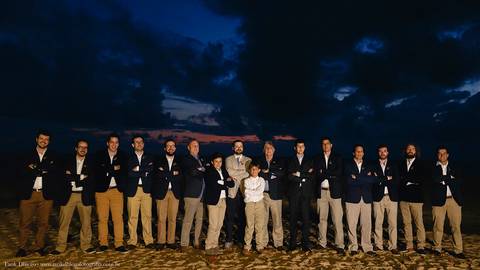 foto do noivo com os padrinhos na areia da Praia com por-do-sol de fundo'