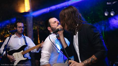 Noivo tocando guitarra e cantando no palco no seu casamento durante a Festa na Reserva Tambá na praia de Toque Toque Pequeno em São Sebastião após a cerimônia do casamento na Praia'