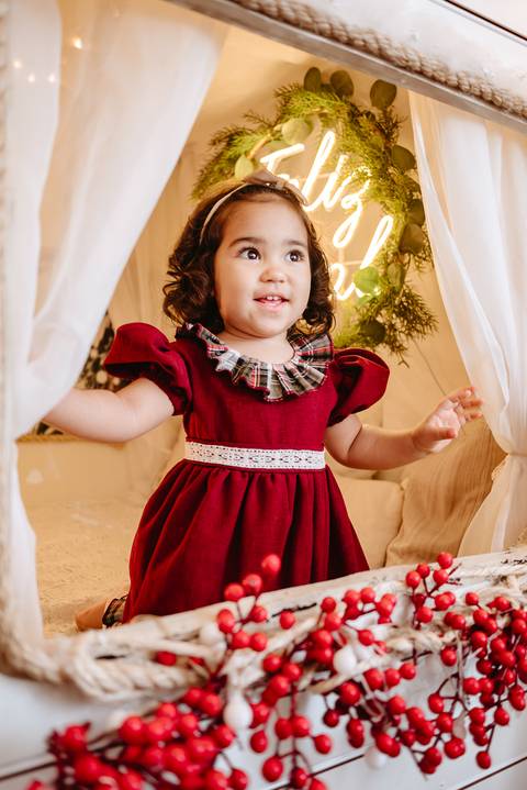 menina de cabelos lisos com mãos apertadas olhando a neve cair de dentro de um trailer'