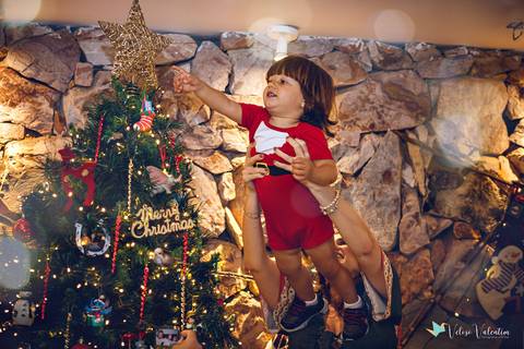 Criança sendo erguida para colocar a estrela na árvore de natal'