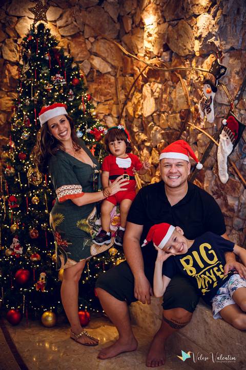 Família posando para foto com árvore de natal'