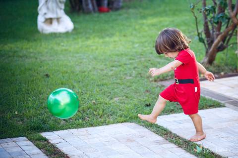 criança chutando bola verde'