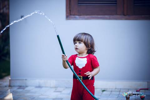 menino segurando mangueira com água'