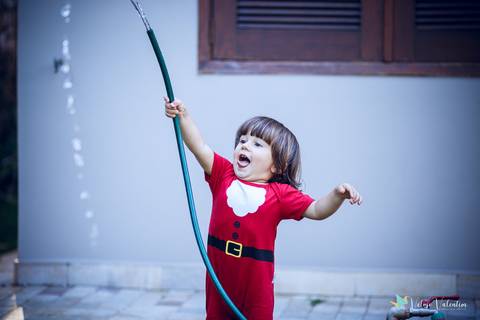 criança rindo brincando com água'