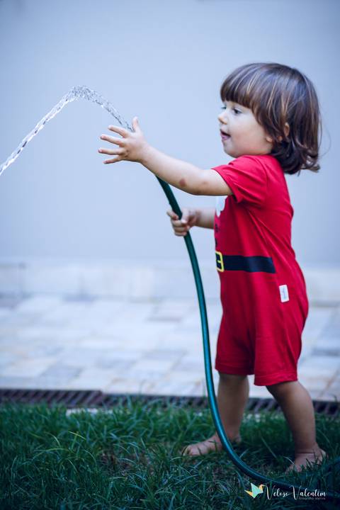 menino com mangueira e roupa de natal'