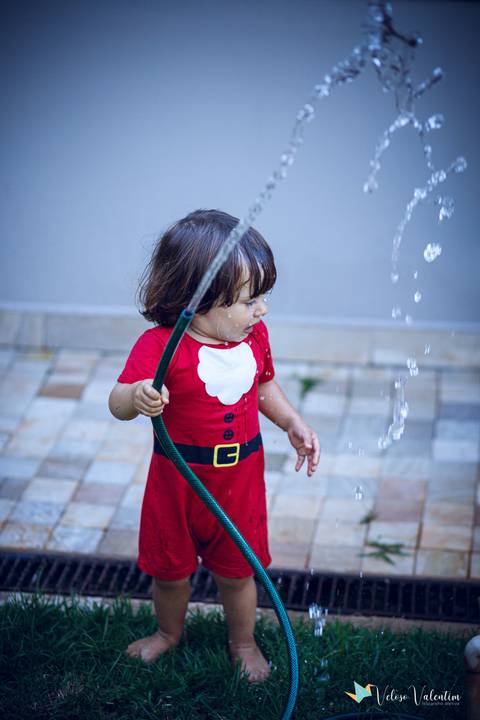 criança se diverte com água da mangueira'