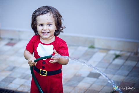 menino de papai noel brinca com mangueira'