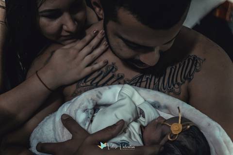 pai e mãe com bebê nos braços'