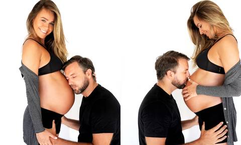 gestante em ensaio fotográfico com calça e top preto e casaco cinza.'