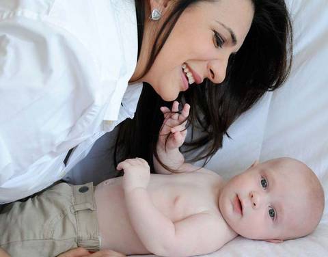 mulher camisa branca, cabelos escuros com bebê.'