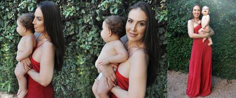 Mulher vestindo vestido vermelho, segurando seu filho no colo.'