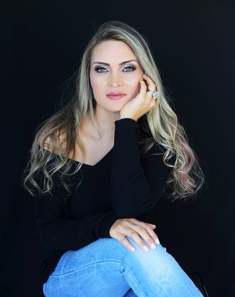 Leila Fraga Saut, cabelos loiros, blusa preta, jóias.'