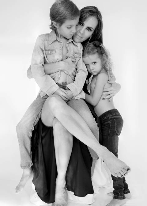 fotografia P&B mãe e filhos, menino com calça e camisa jeans e menina com calça jeans. '