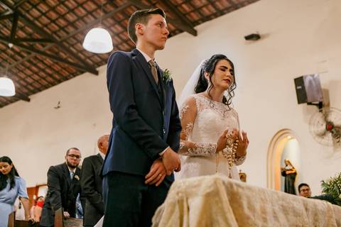 noivo e noiva no altar recebendo as bençãos do padre no casamento religioso'