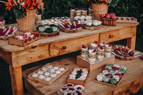 Decoração com mesa de madeira e flores em tons vivos para mesa do bolo'