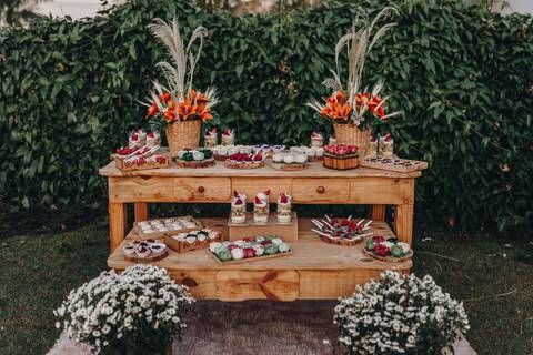 Decoração com mesa de madeira e flores em tons vivos para mesa do bolo'
