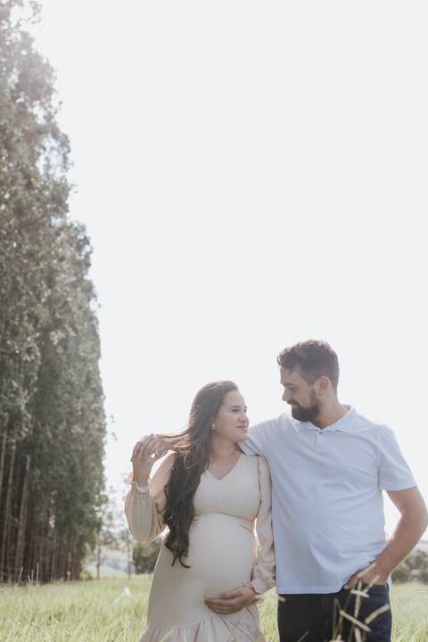 casal caminhando no campo em ensaio de gestante'