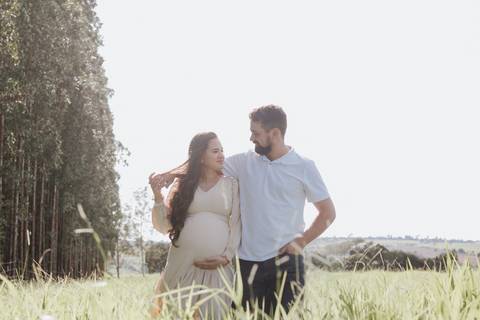 casal caminhando no campo em ensaio de gestante'