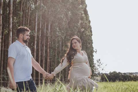 casal caminhando no campo em ensaio de gestante'