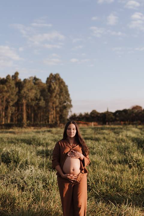 ensaio de gestante no campo com por do sol'