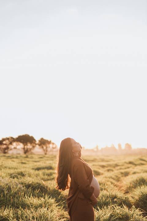 ensaio de gestante no campo com por do sol'