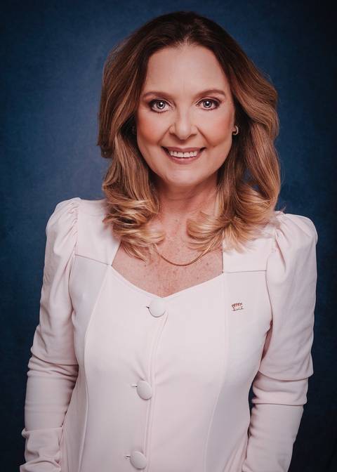 fotografia de marca pessoal em Niterói para dentista. A dentista está de frente para a camera, fundo azul, sorrindo para a camera transmitindo orgulho e autoridade.'