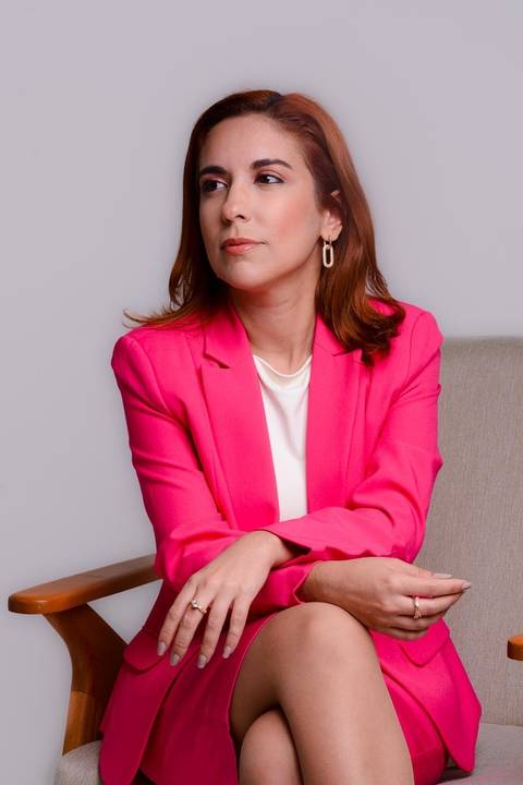 ensaio corporativo feminino em estúdio. Ela está sentada em uma cadeira olhando para o lado direito em pose que transmite poder e liderança.'