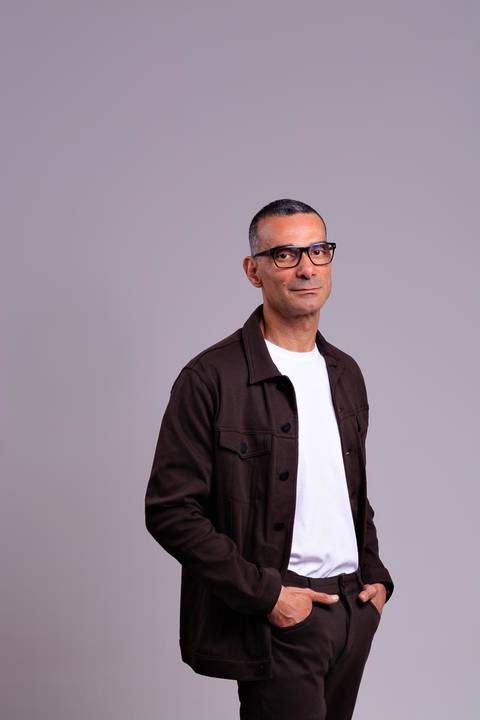 Médico fotografado em estúdio fotográfico no centro de Niterói vestindo jaqueta marrom camiseta básica branca.'