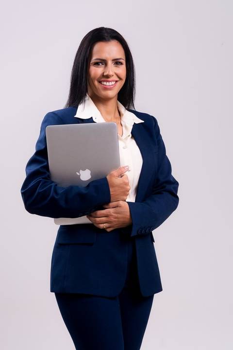 ensaio de advogada em estúdio no centro de Niterói. A advogada está em pé e segura seu computador.'