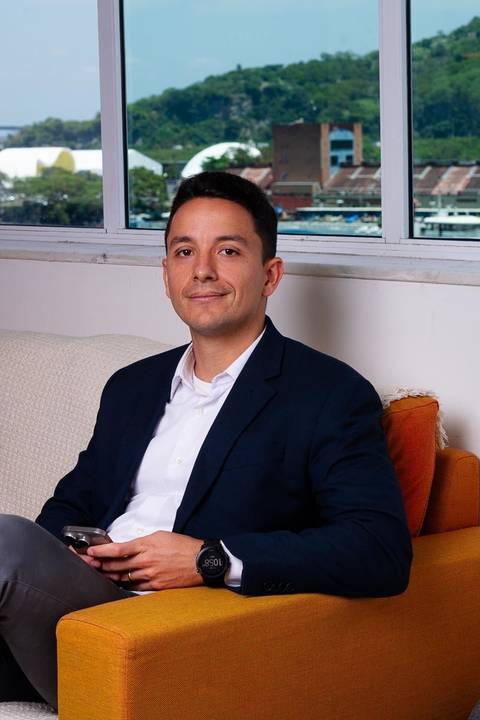 ensaio em estúdio de advogado em estúdio no centro de Niterói sentado em poltrona e ao fundo vista para o centro de niterói.'