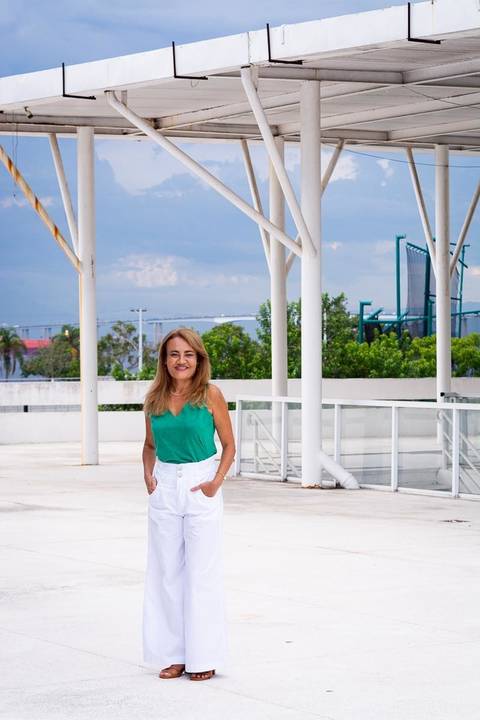 Foto de corpo inteiro de psicóloga em ambiente moderno e claro. Transmite transparência, clareza e profissionalismo.'