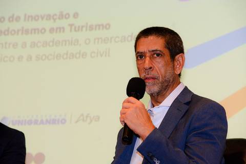 Close profissional de palestrante durante evento de inovação e turismo no Rio de Janeiro.'