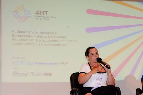 Close profissional de palestrante durante evento de inovação e turismo no Rio de Janeiro.'