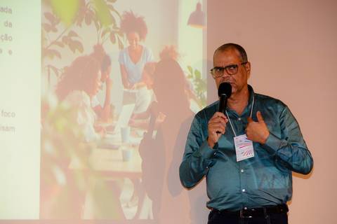 Close profissional de palestrante durante evento de inovação e turismo no Rio de Janeiro.'