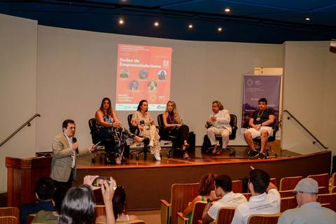 Registro profissional de conferência sobre transformação digital no turismo, destacando palestrantes e apresentação visual.'