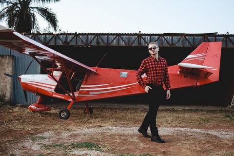 Modelo olhando para o lado vestindo looks para fotografia ao lado de um avião'