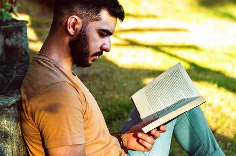 Ensaio masculino externo com livros e violão Agência Cricaré'