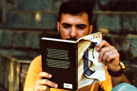 Ensaio masculino externo com livros e violão Agência Cricaré'