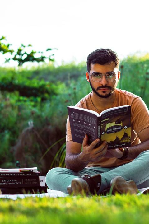 Ensaio masculino externo com livros e violão Agência Cricaré'