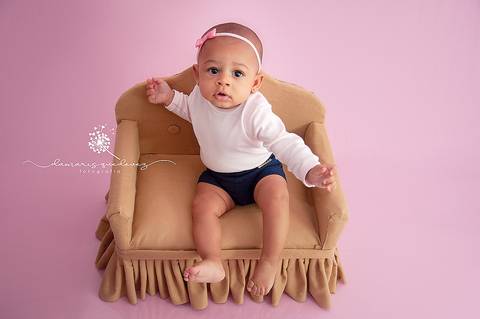 Sessão de acompanhamento da Graziella com 6 meses, no fundo rosa, sentada no sofázinho olhando para cima. Ensaio realizado em Barra Mansa - Newborn Acompanhamento Gestante e Família - Volta Redonda'