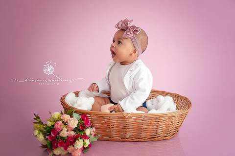 Sessão de acompanhamento da Graziella com 6 meses, no fundo rosa, sentada no cestinho com flores. Ensaio realizado em Barra Mansa - Newborn Acompanhamento Gestante e Família - Volta Redonda'