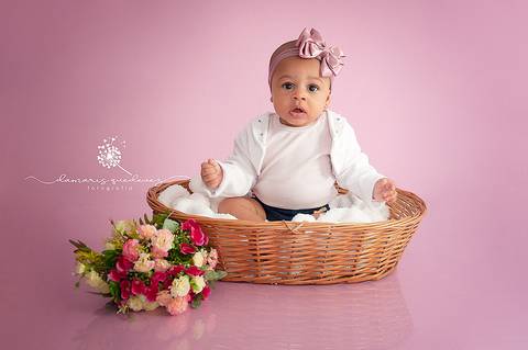 Sessão de acompanhamento da Graziella com 6 meses, no fundo rosa, sentada no cestinho com flores. Ensaio realizado em Barra Mansa - Newborn Acompanhamento Gestante e Família - Volta Redonda'
