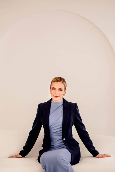 Retrato executivo da Dra. Lara Poltronieri, com blazer azul-marinho e composição minimalista que valoriza sua presença profissional.'