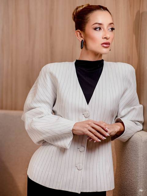 Fotografia de posicionamento da biomédica Katiane Soares em blazer branco com risca de giz e blusa preta, destacando a composição sofisticada e a elegância de sua imagem profissional.'