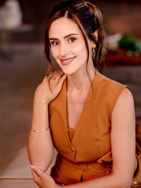 Retrato profissional da dentista Fernanda Wisniewski em traje caramelo, com sorriso delicado e mão próxima ao rosto, revelando naturalidade e elegância na fotografia de posicionamento.'